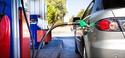 Silver car at retailer gas station pumping gas